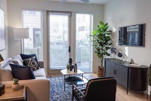 A living room with a couch, chair, and a table with a plant on it.
