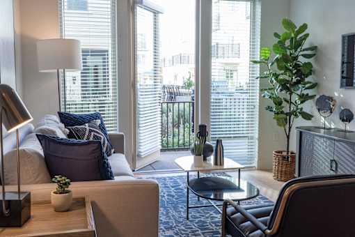 A living room with a couch, chair, and a table with a lamp and a plant on it.