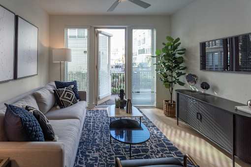 A living room with a white couch and a blue rug.