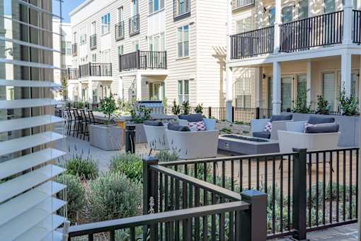 A patio area with white chairs and a black railing.