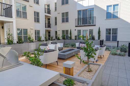 A patio area with a table and chairs is surrounded by apartment buildings.