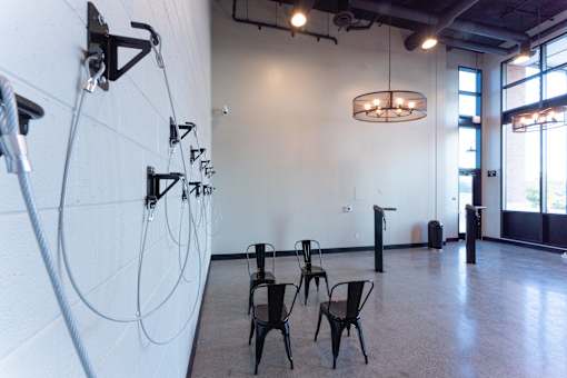 A room with a white wall and a row of black chairs.