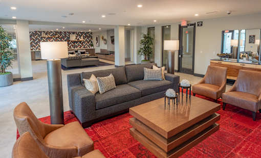 A living room with a grey couch, a brown chair, and a wooden coffee table.