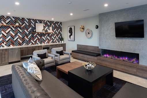 A modern living room with a grey couch and a fireplace.