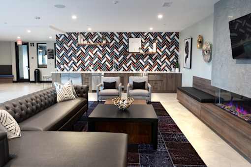 A modern living room with a black leather sofa and a patterned wallpaper.