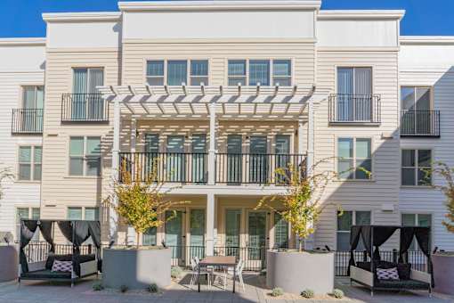 A modern two-story apartment building with a balcony and outdoor seating area.