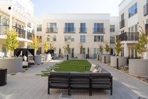 A black bench sits in the middle of a courtyard with apartment buildings in the background.