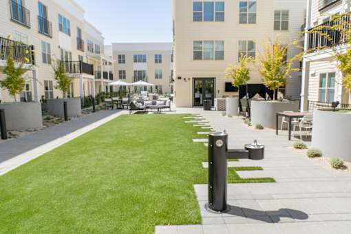 A grassy area in front of apartment buildings with a black pole in the foreground.