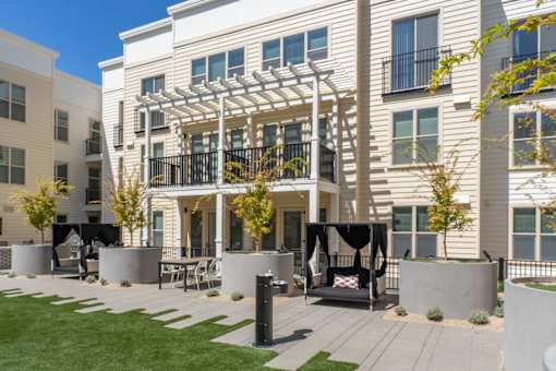 A modern building with a white facade and a balcony with a pergola.
