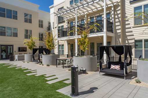 A modern outdoor seating area with a black swing chair and a white cushion.
