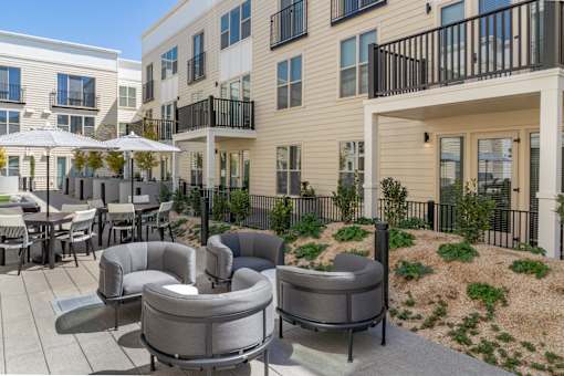 A patio with grey furniture and a white umbrella.
