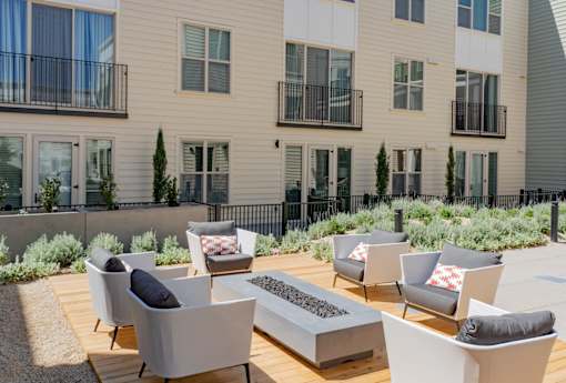 A patio with grey chairs and a fire pit.