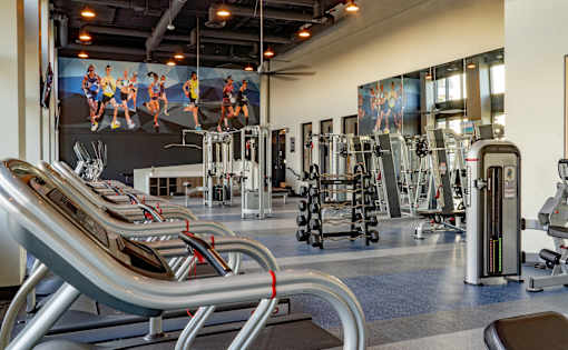 A gym with a variety of equipment including treadmills, weights, and exercise machines.
