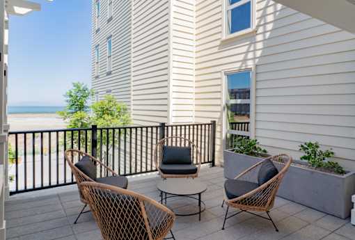 A balcony with a table and chairs overlooking the ocean.