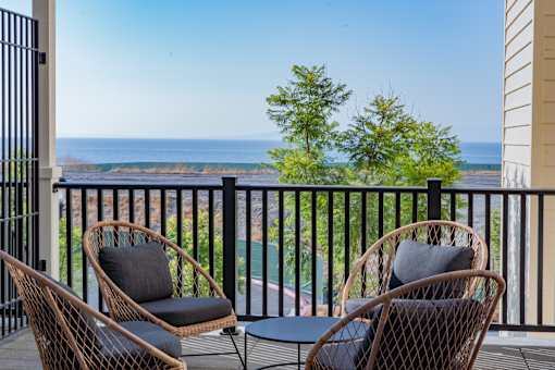 Two chairs and a table on a balcony overlooking the ocean.