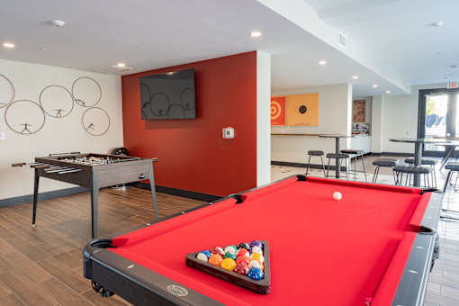 A pool table with a red cloth and a set of balls on it.
