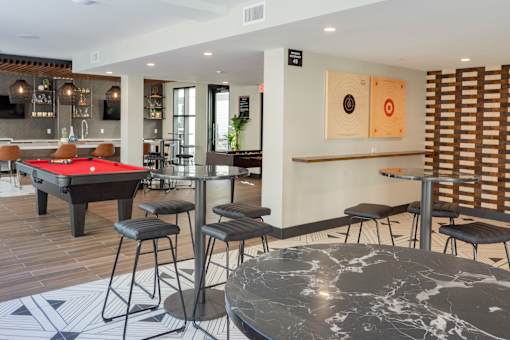 A room with a pool table and bar stools.