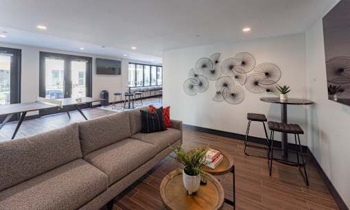A living room with a couch, a chair, and a table with a potted plant on it.