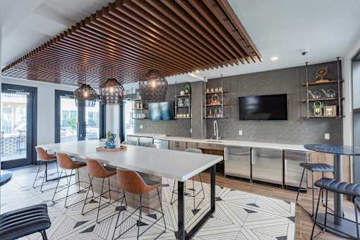 A modern kitchen with a long white table and chairs.