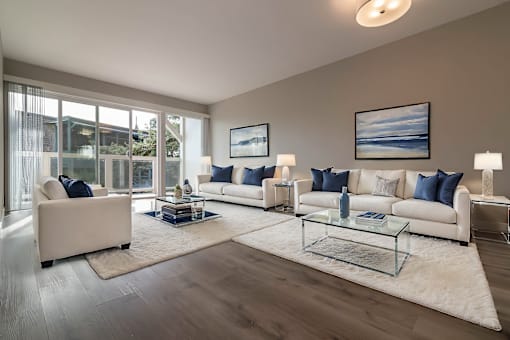 A living room with a large window, a white sofa, a glass coffee table, and a rug at The Pier at Sausalito, Sausalito, CA