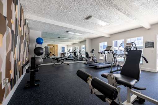 a gym with weights and other exercise equipments in a room with a large window at Campbell West Apartments, California 95008