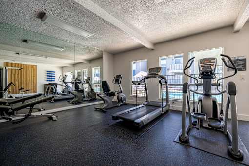 a gym with cardio machines and weights on the floor at Campbell West Apartments, California