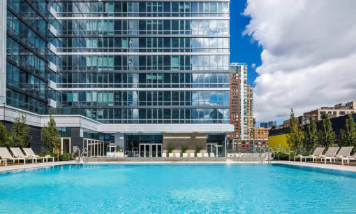 a swimming pool in front of a tall building at SKY Apartments, New York, NY