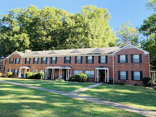 the front of a brick house with grass and trees