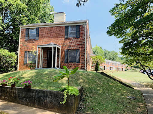 an old brick house on a hill with a lawn and a sidewalk
