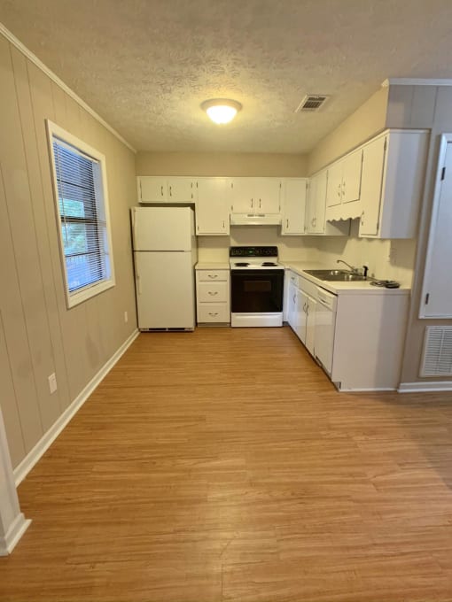 a kitchen with white appliances and a wooden floor