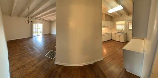 an empty living room and kitchen with wood floors