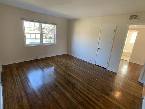 an empty living room with wooden floors and a window