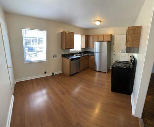 an empty kitchen with wooden floors and stainless steel appliances