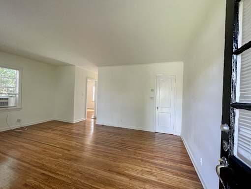 an empty living room with wood floors and white walls