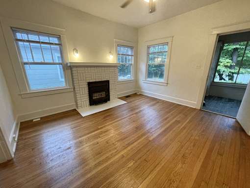 an empty living room with wood floors and a fireplace