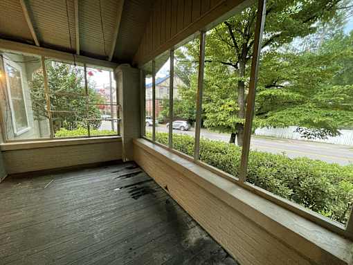 a large porch with large windows overlooking a street and trees