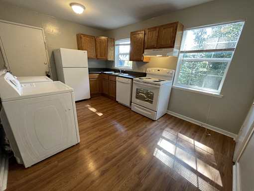 an empty kitchen with wood floors and white appliances