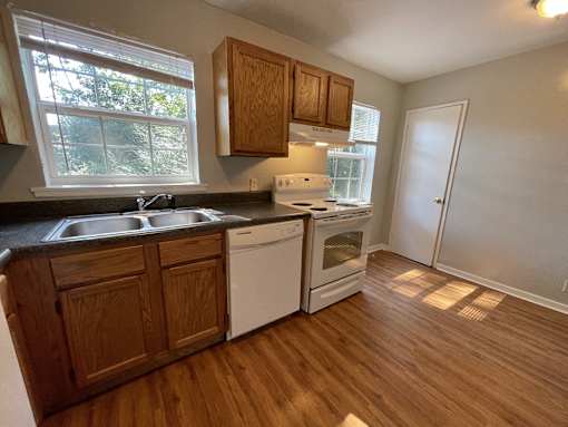 an empty kitchen with wooden flooring and a window