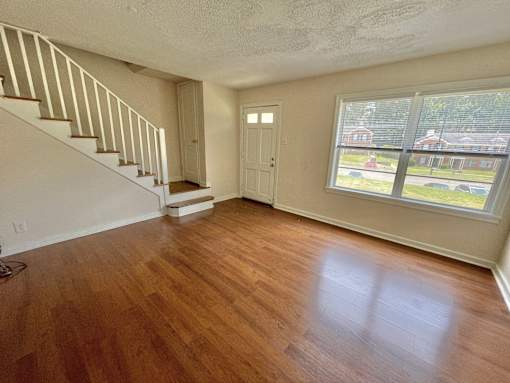an empty living room with a hard wood floor and a staircase