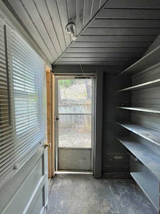 the inside of a tiny house with a door and shelves