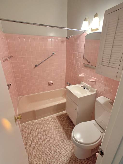 a pink bathroom with a toilet and a bath tub