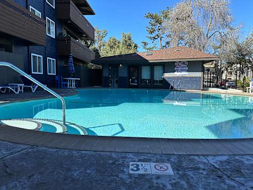 A swimming pool with a slide and a building in the background.