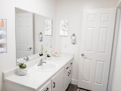 A white bathroom with a sink and mirror.