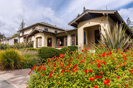 a house with a driveway and flowers in front of it