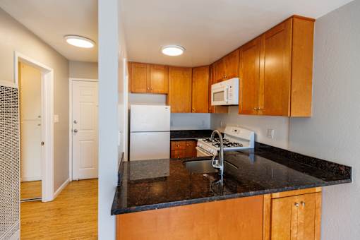 A kitchen with wooden cabinets and a black countertop.