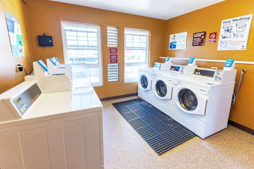 A laundromat with a washer and dryer and a flat screen TV.