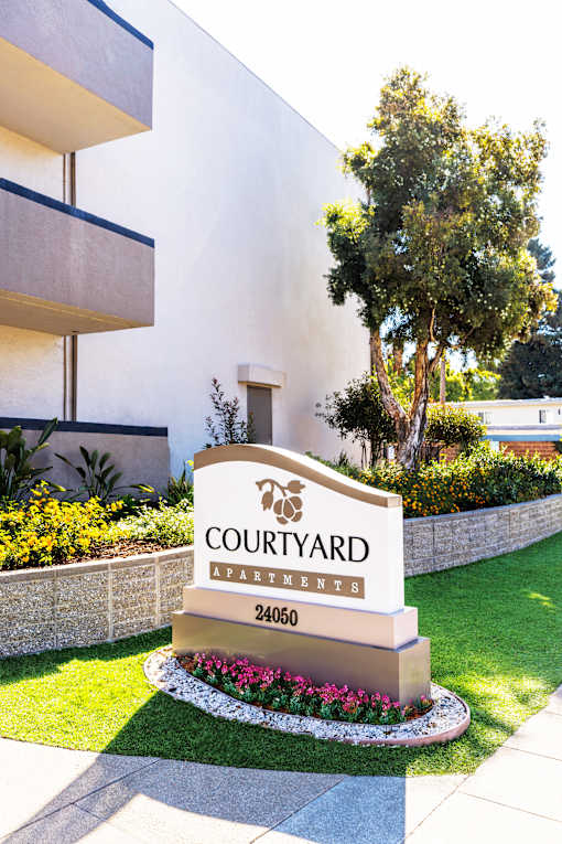 A sign for Courtyard Apartments is in front of a building.