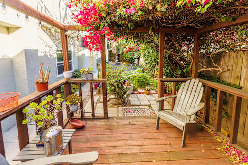 A wooden deck with a bench and a table with flowers on it.