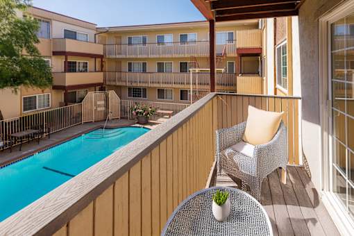 A balcony with a table and chairs overlooking a pool.