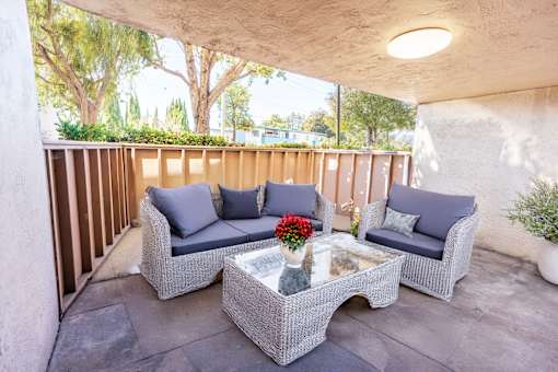 A patio with a grey couch, a grey sofa, and a grey coffee table.
